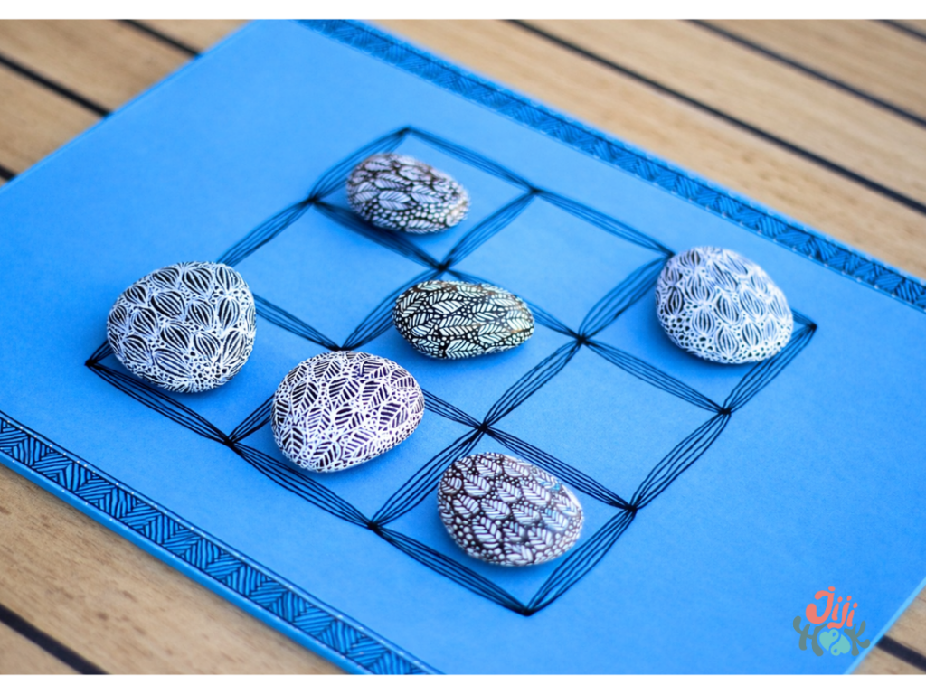 Loisirs créatifs enfants : galets décorés de motifs Zentangle posés sur une tuile bleue, activité créative apaisante