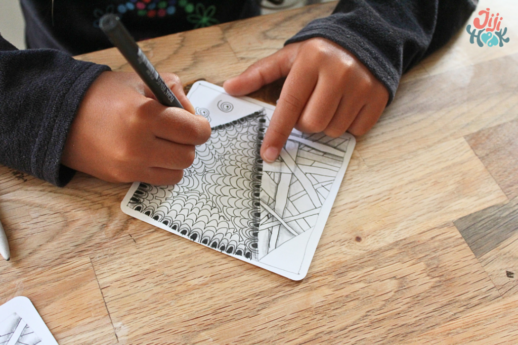 Loisirs créatifs enfants : enfant dessinant une tuile Zentangle au feutre noir, activité de concentration et relaxation