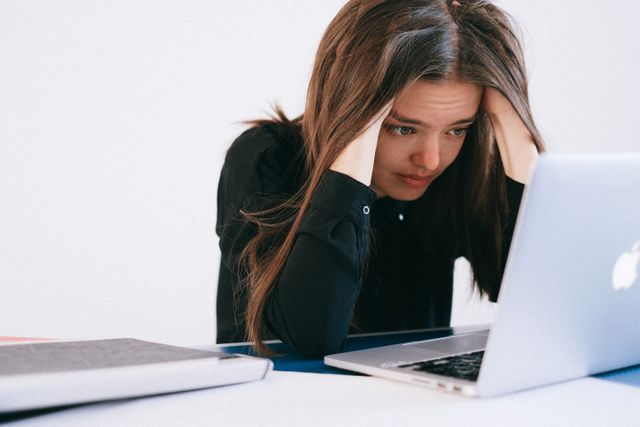une jeune femme qui se tient la tête devant un ordinateur portable, comment destresser